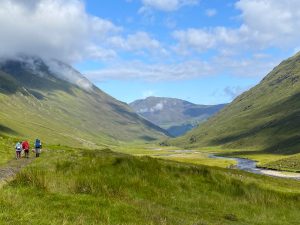 A grass covered valley through some mountains
