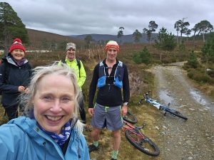 4 mountainbikers, standing at trhe side of a trail