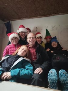 Several tired hillwalkers indoors, wearing Christmas hats